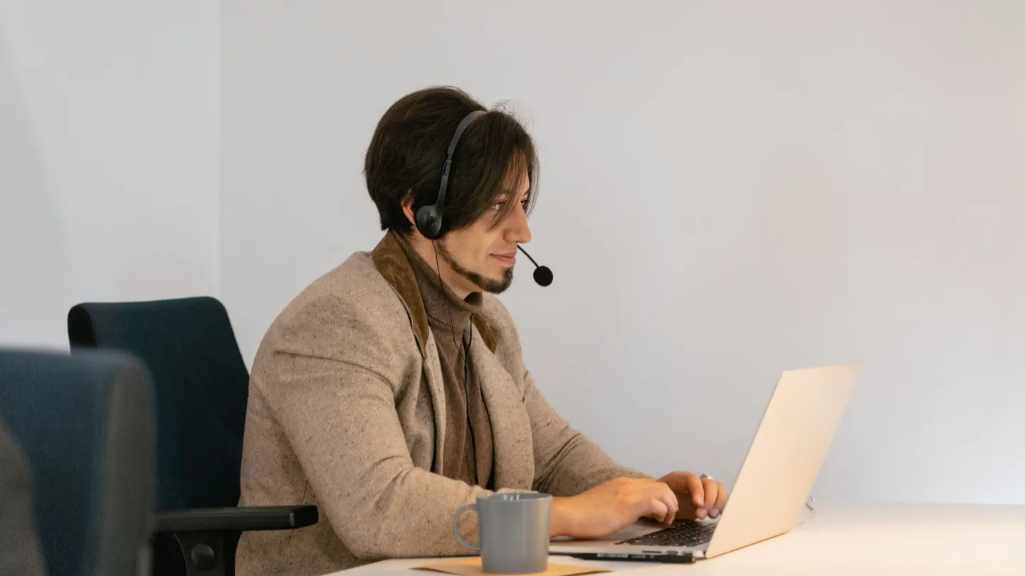 Virtual assistant wearing a headset while reviewing CRM records and duplicate contact cleanup notes.